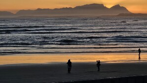 A beach with waves and a sunset. - Searenity Tides - Two Bedroom Apartment, Sleeps 4 (Cape Town)