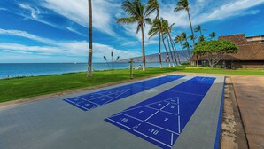 Ein Shuffleboardfeld mit freiem Blick auf das Meer und Palmen.
