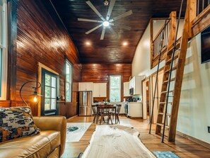 A spacious living area with a wooden ceiling, a ceiling fan, a dining table with chairs, and a kitchen area with cabinets and appliances. - Corton Lodge Riverview Suite – Private Riverfront (Clendenin)