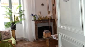 A room with a fireplace, a chandelier, a green sofa, and a potted plant.