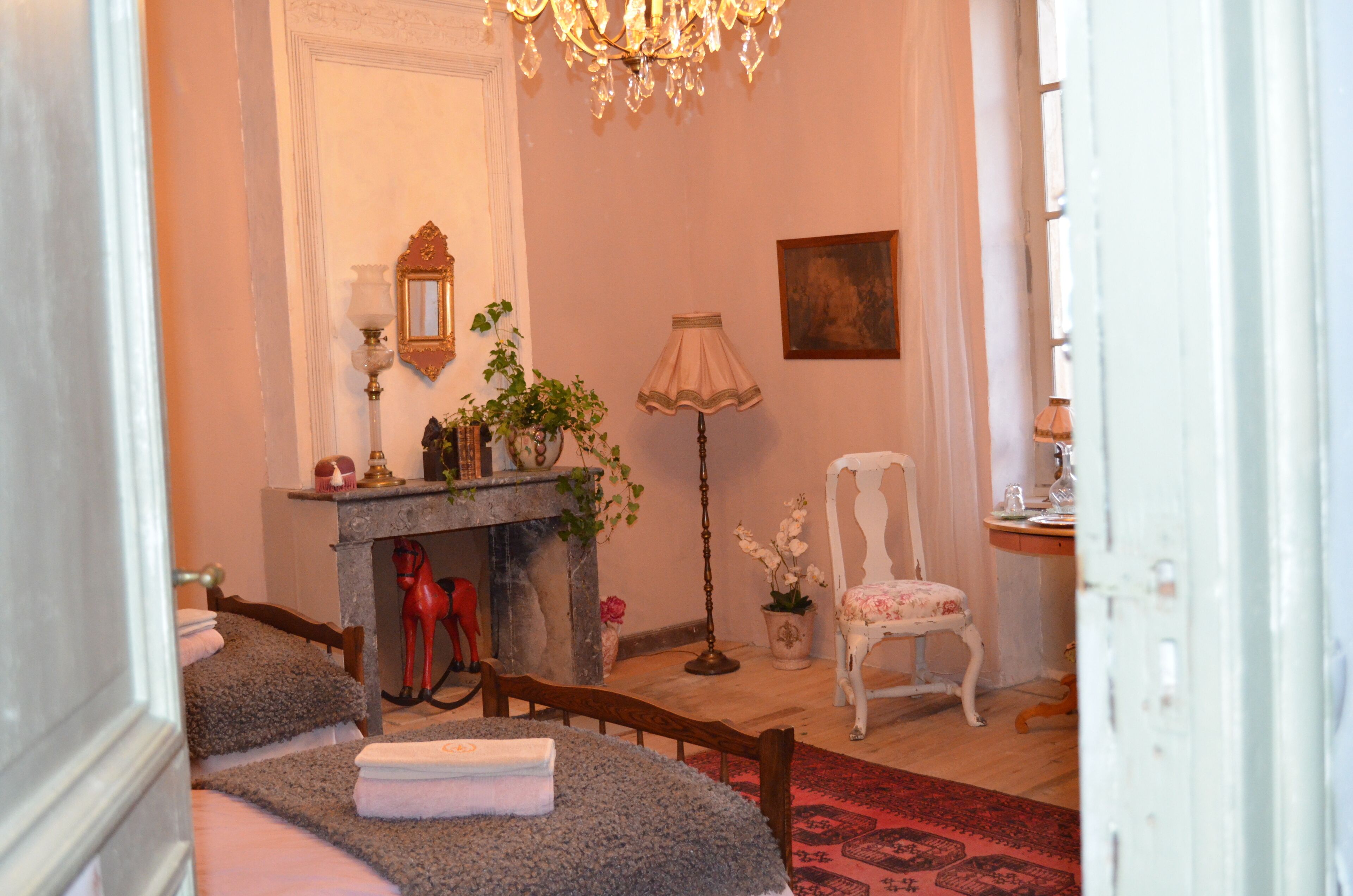 A room with a fireplace, a chair, a table with a towel, and a chandelier.
