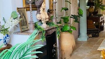 A hallway with a fireplace, framed artwork, and potted plants.