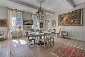 Comedor con candelabro, un cuadro grande y una mesa lista para cuatro comensales.