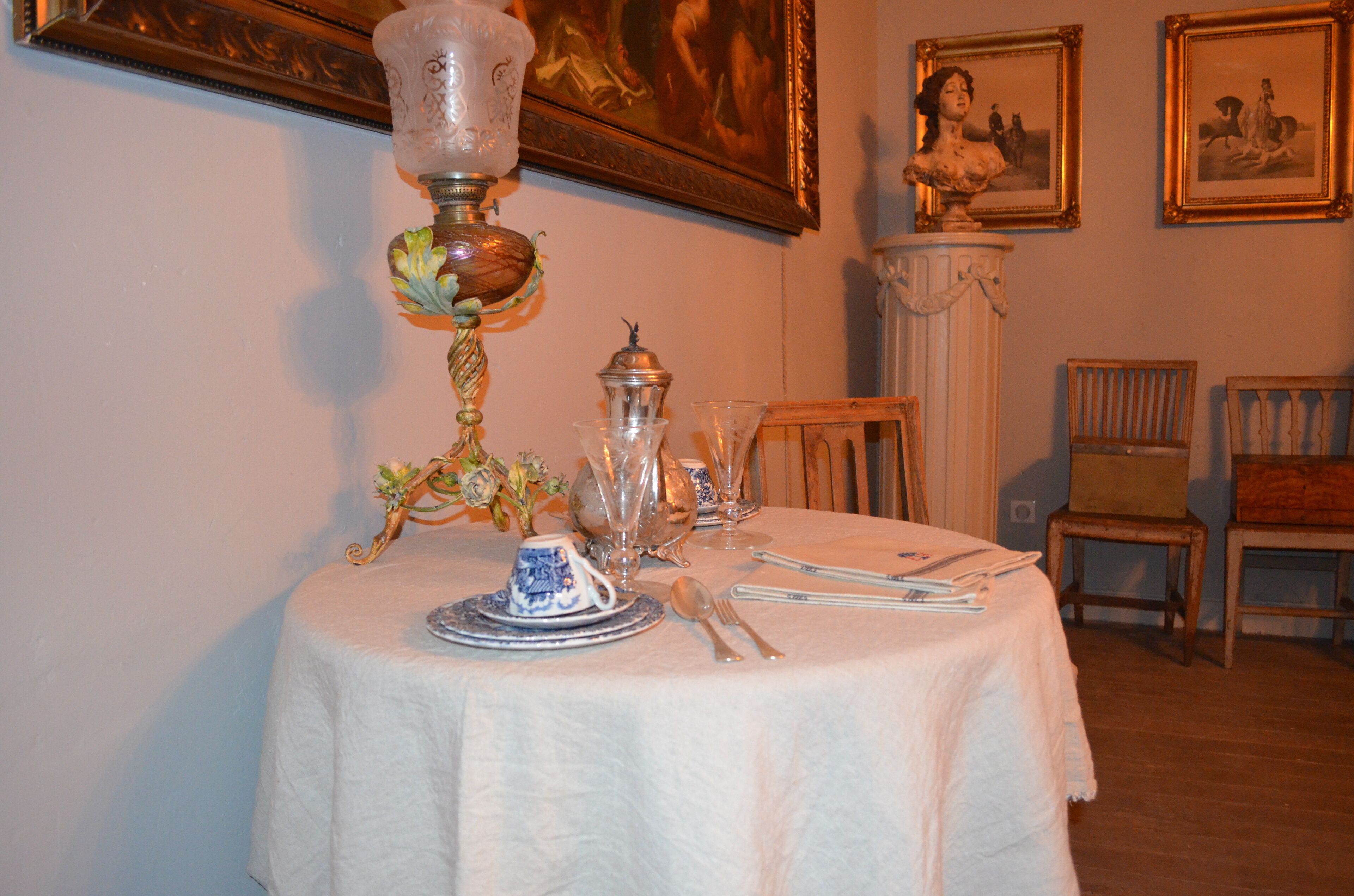 A dining table set with fine china, silverware, and a decorative lamp.