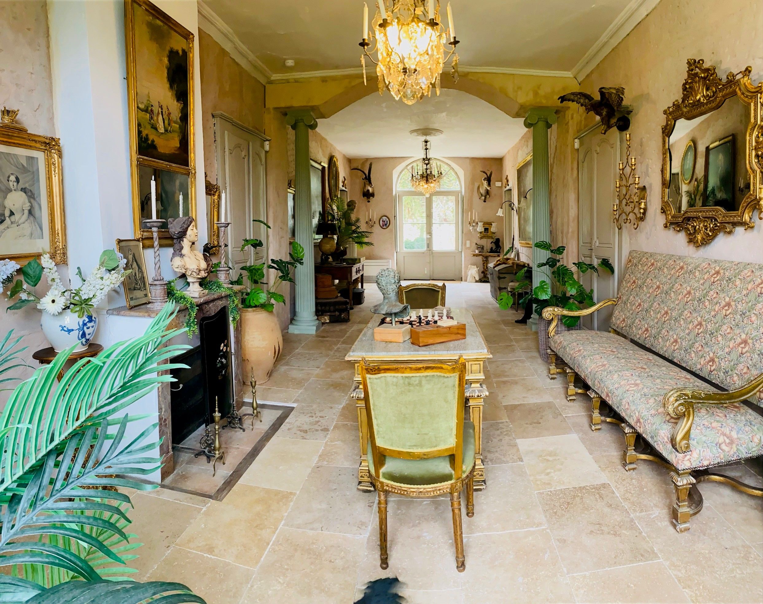 Un salón elegante con candelabro, muebles ornamentados y un tablero de ajedrez.