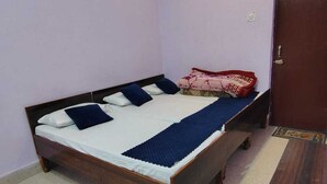 A single bed with a wooden frame, white bedding, and a blue blanket.