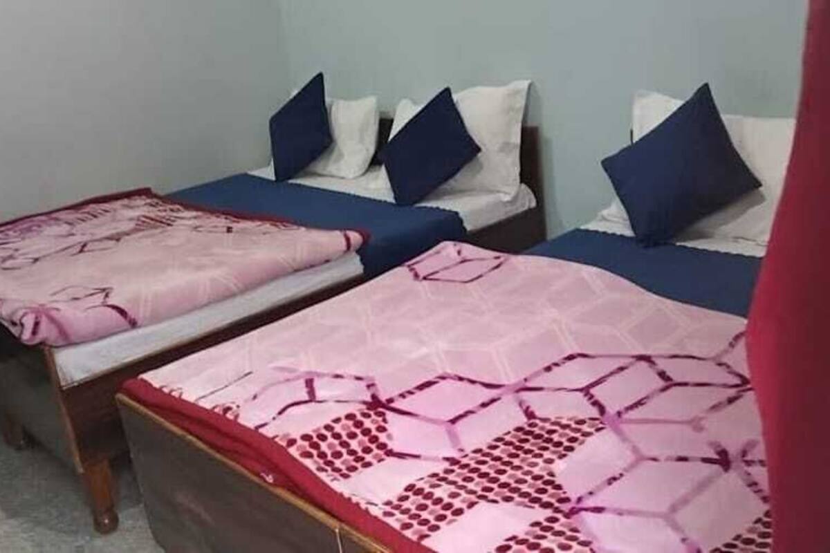 A room with two single beds, each with a pink patterned bedspread and blue pillows.