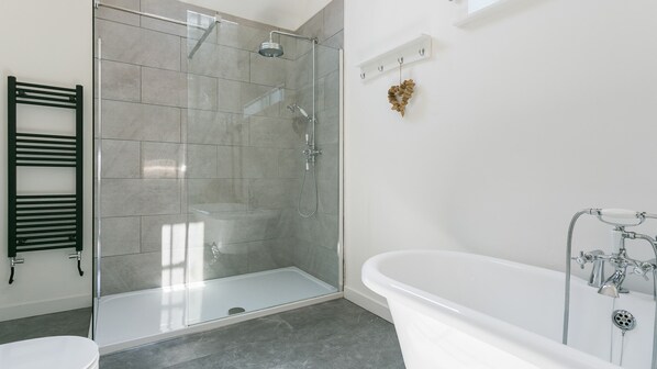 A modern bathroom with a glass-enclosed shower, a freestanding bathtub, and a towel rack.
