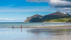 Una playa con una montaña al fondo, agua tranquila y algunas personas.