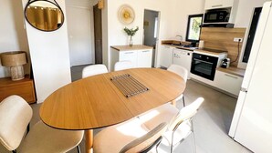Une cuisine moderne avec des meubles blancs, une table à manger en bois et un four encastré.