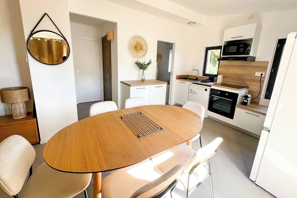Una cocina moderna con armarios blancos, una mesa de comedor de madera y un horno empotrado.