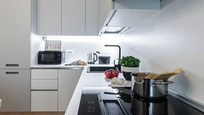 A modern kitchen with white cabinets, a microwave, a kettle, a sink, and a pot of pasta. - Italianway Comfort - Cialdini 85 (Milano)