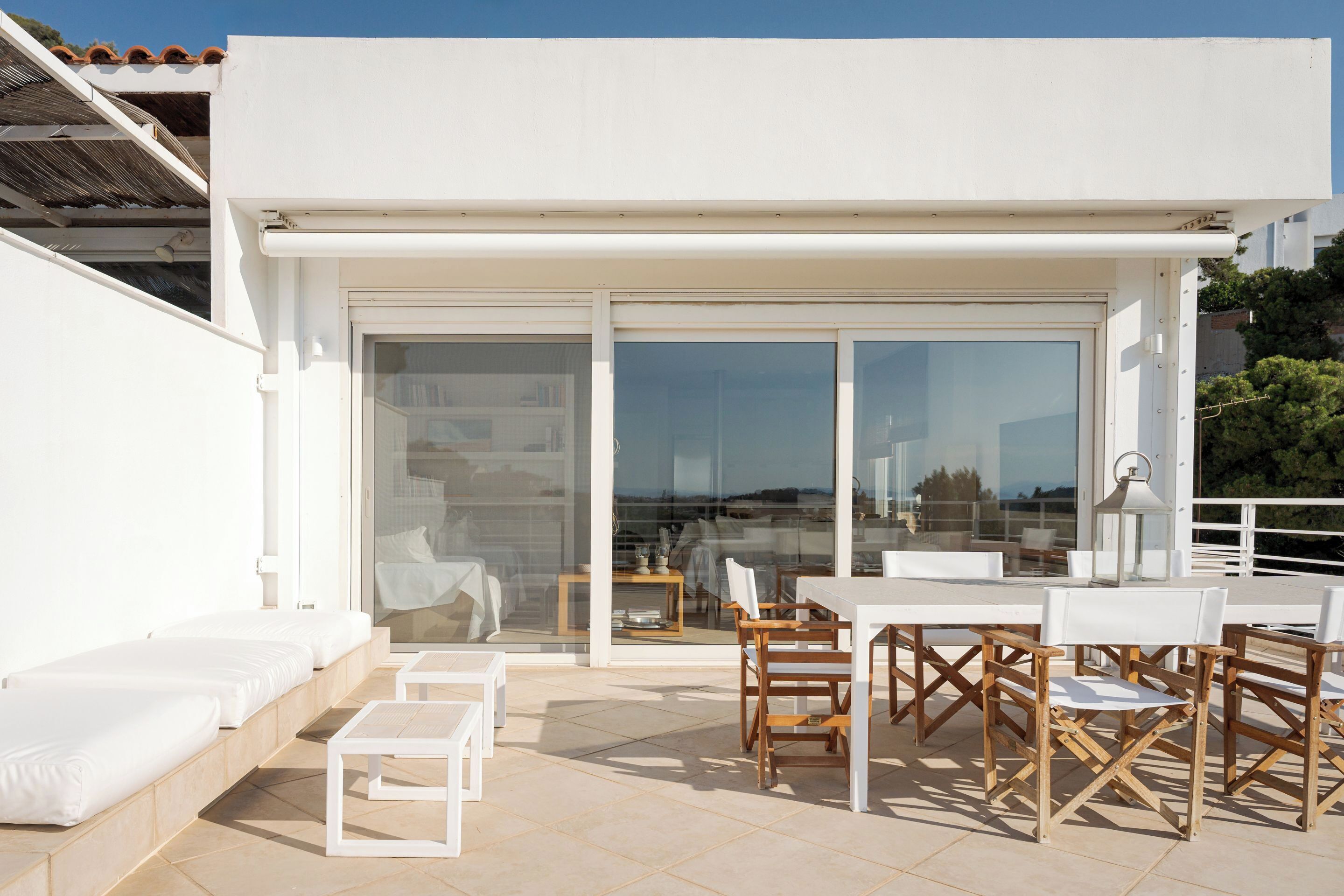 Une terrasse extérieure meublée de mobilier blanc, comprenant des canapés et une table avec des chaises.
