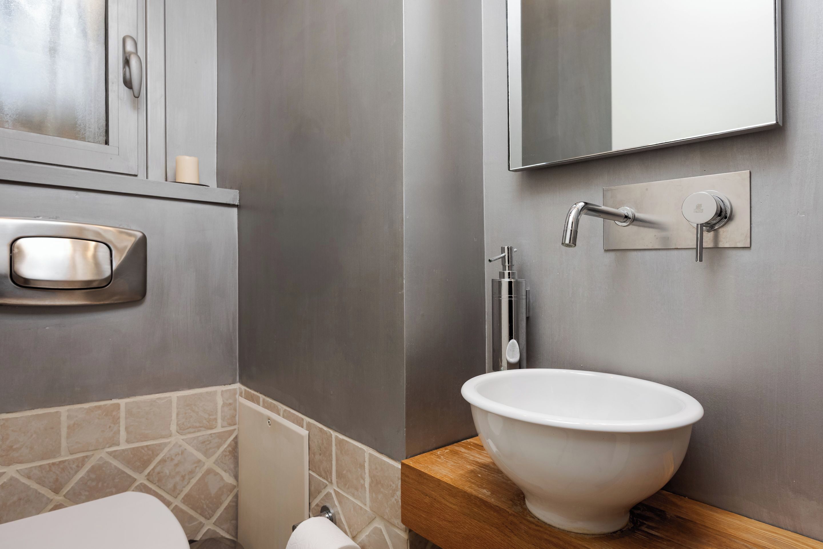 A modern bathroom with a white sink, a mirror, and a toilet.