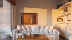 A modern living room with a white sofa, a wooden coffee table, and a painting on the wall. - Vouliagmeni Exclusive Residence (Vouliagmeni)
