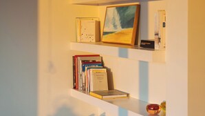 A bedroom with a bed, a white dresser, and a bookshelf with books and a framed picture. - Vouliagmeni Exclusive Residence (Vouliagmeni)