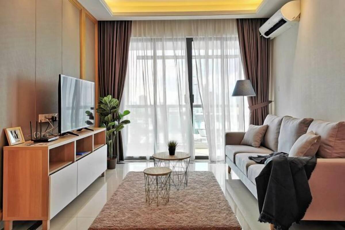 A modern living room with a sofa, TV, and a small table with a plant.