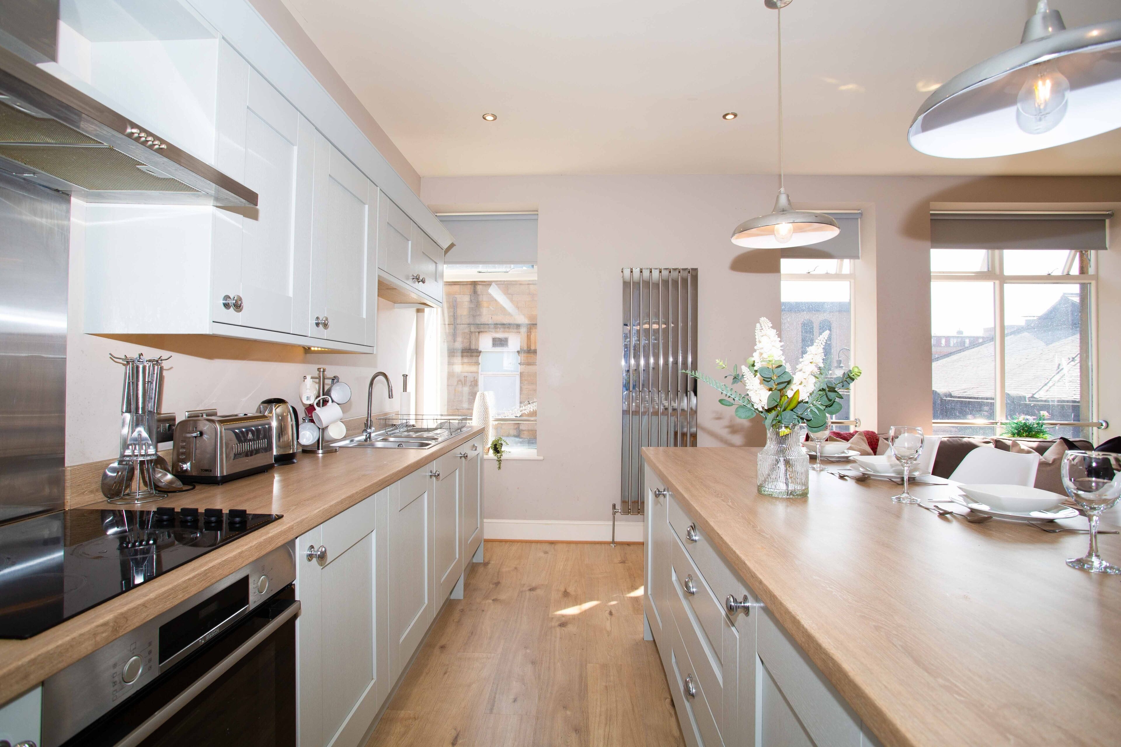 A modern kitchen with stainless steel appliances, wooden countertops, and a dining area with a vase of flowers.