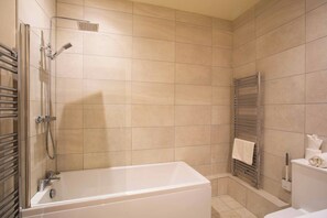 A modern bathroom with a bathtub, shower, and towel rack.