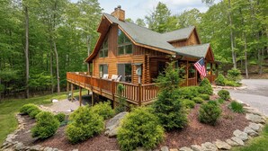 Une cabane en rondins dotée d’une terrasse, entourée d’une forêt.