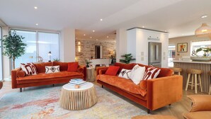 Un salon moderne avec deux canapés orange, une table basse et un tapis coloré.