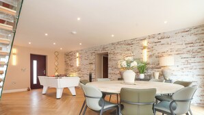 Un espace repas moderne avec une table ronde, six chaises et une table de billard.