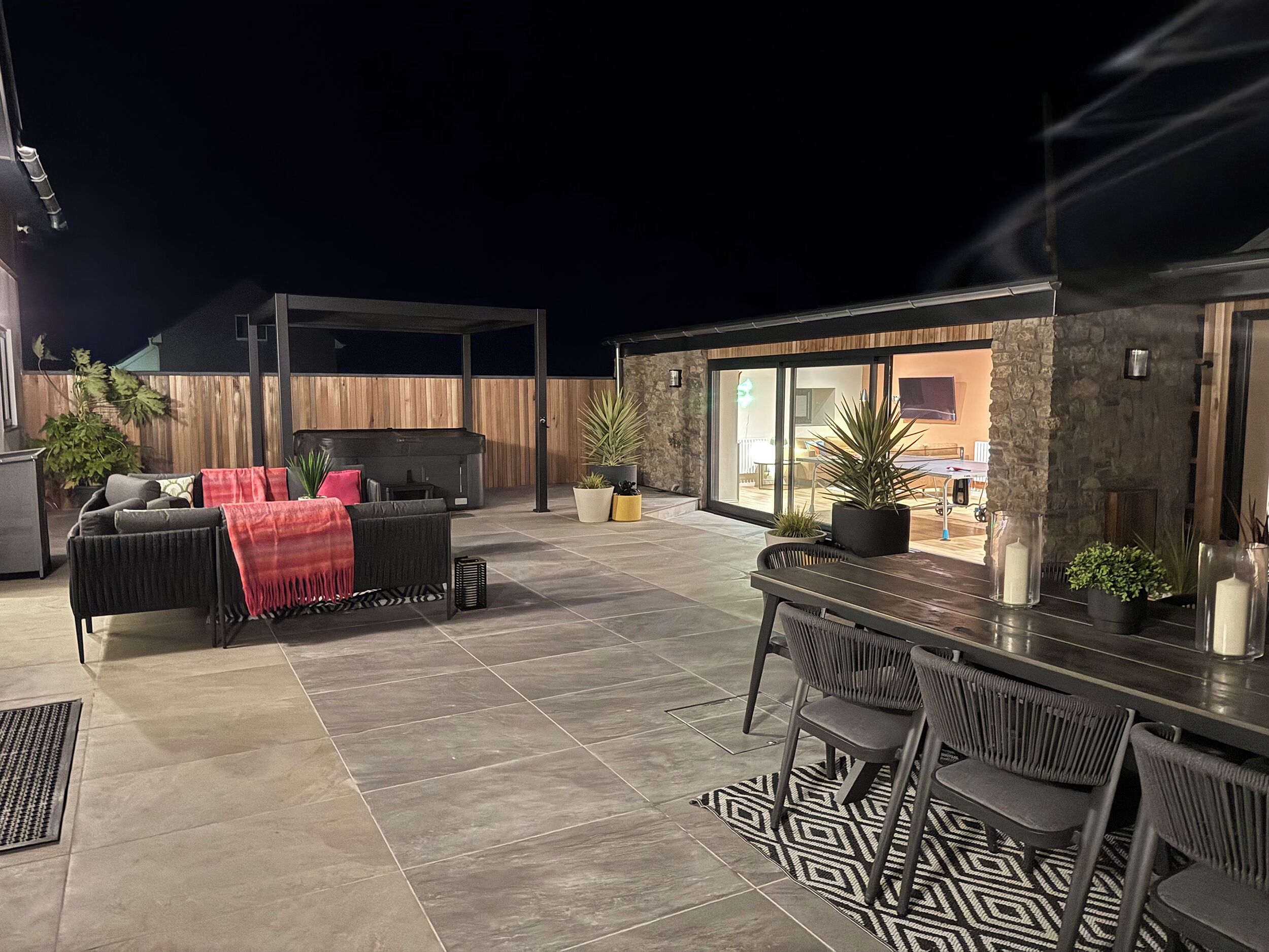 Un patio con una parrilla, mobiliario exterior y plantas en macetas.