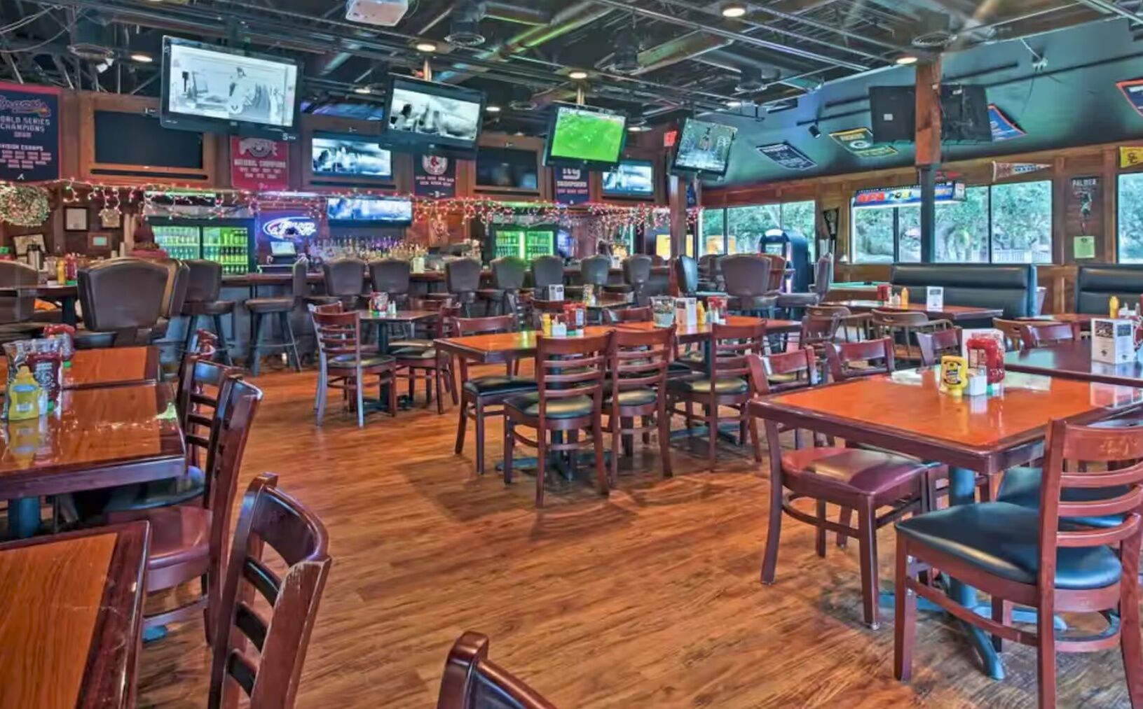 Un restaurant doté de nombreuses tables et chaises, de téléviseurs fixés au plafond et d’un plancher en bois.