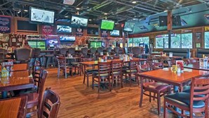 A restaurant with multiple tables and chairs, televisions mounted on the ceiling, and a wooden floor. - Stylish Oceanview Getaway – Just Steps to Beach & Oceanside Pool (Hilton Head Island)
