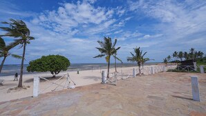 A beach with palm trees, a stone pathway, and a view of the ocean. - Serene 2bedroom Beach Apartment, Sultanpalace Kikambala. Northcoast Kilifi Kenya (Kikambala)