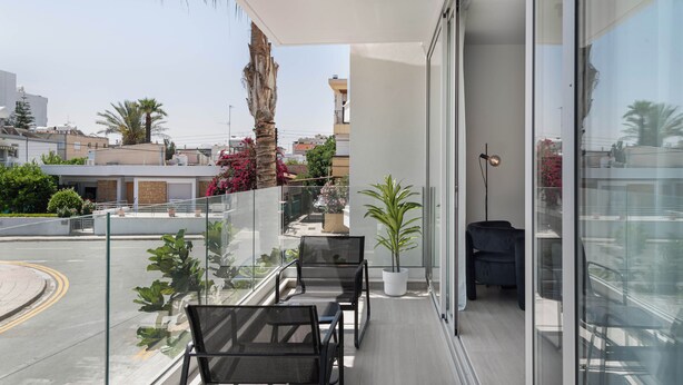 Ein Balkon mit Glasgeländern, einem Deckenventilator und einem Blumentopf.
