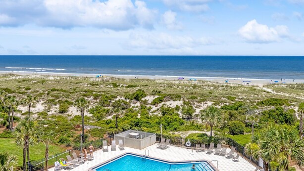 A pool area with a view of the beach and ocean.