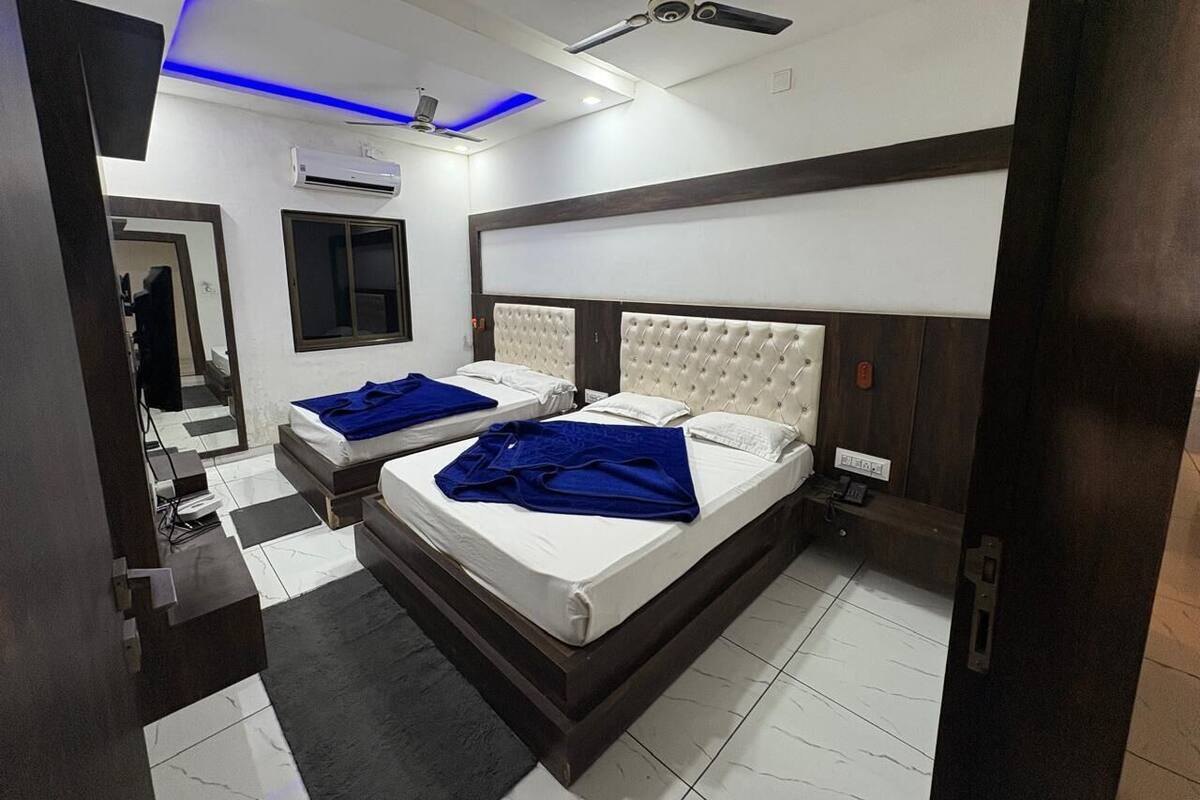 A hotel room with a large bed, a smaller bed, a ceiling fan, and a modern design with blue lighting.