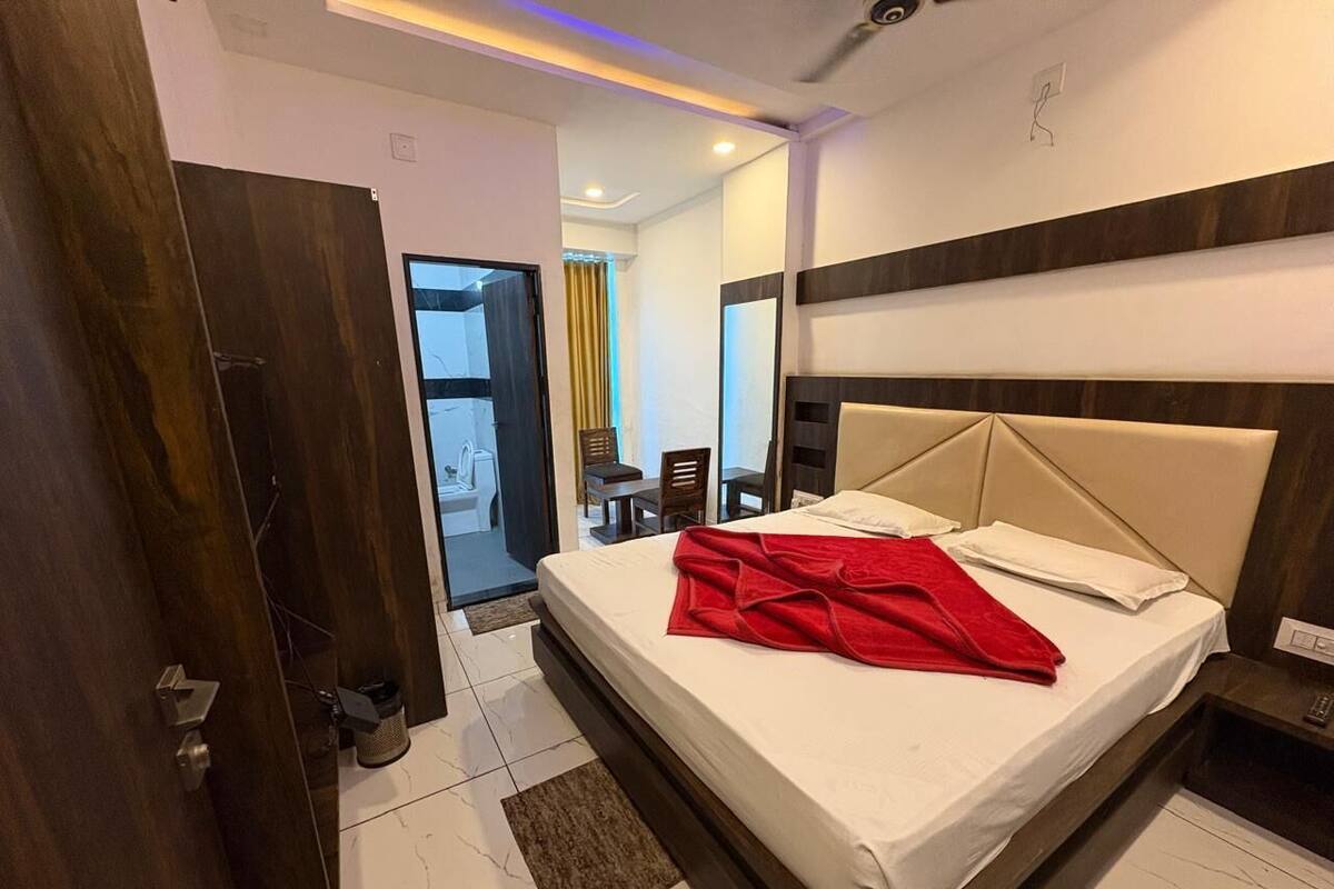 A hotel room with a bed, a wooden door, a small table, and a chair.