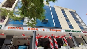 Un hotel con fachada moderna, un restaurante y una entrada visible con decoraciones rojas y blancas.