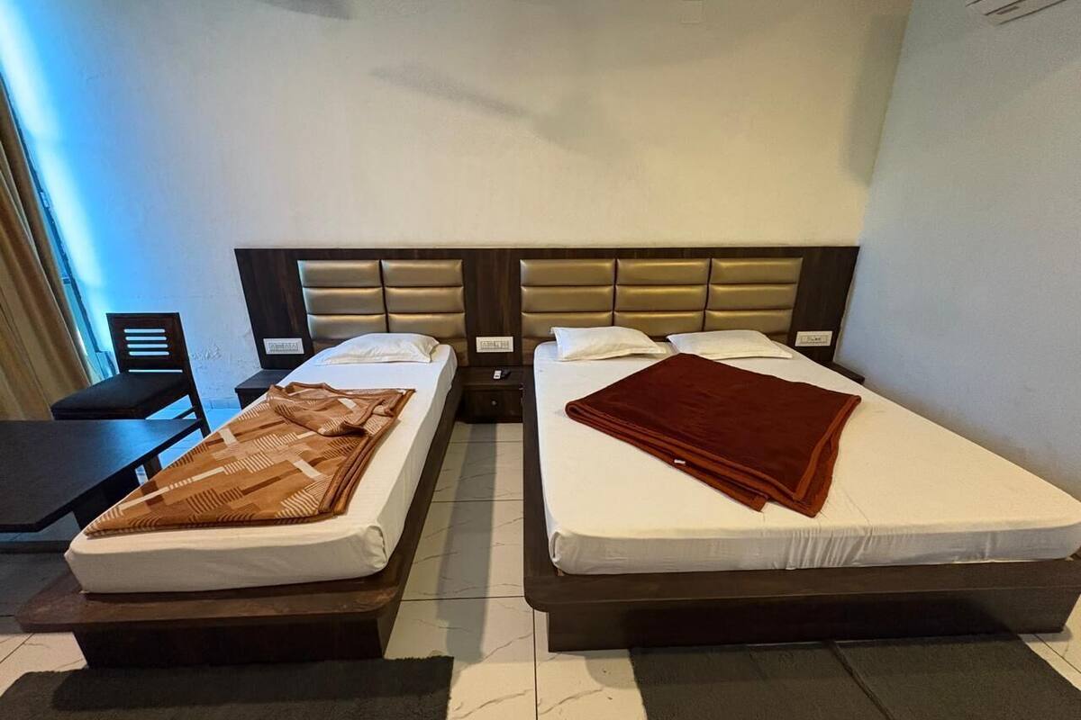 A hotel room with two beds, a desk, and a chair.