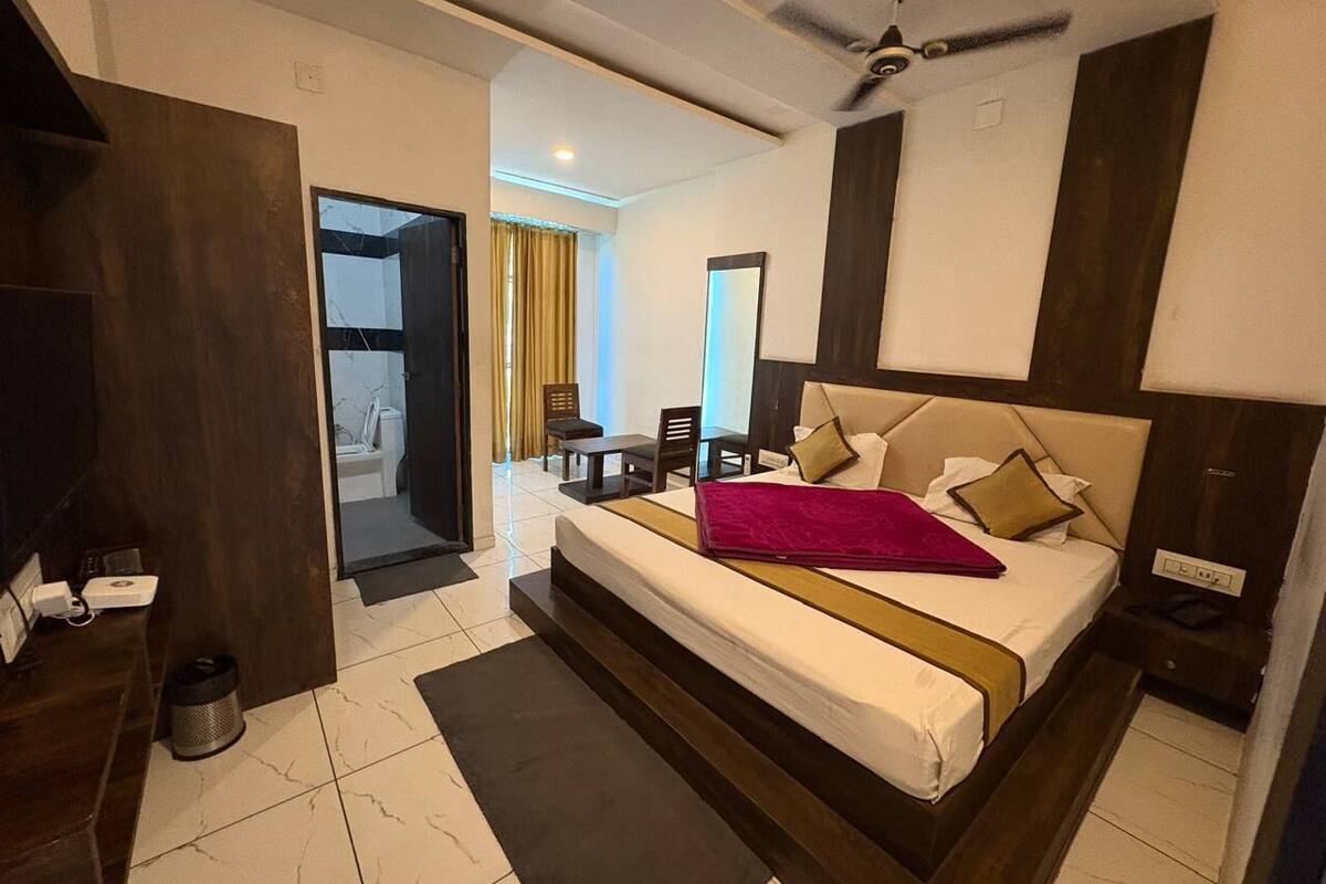 A modern hotel room with a large bed, a ceiling fan, and a view of the bathroom.