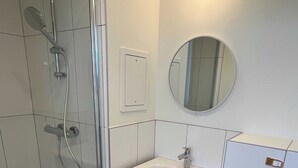 A bathroom with a glass shower enclosure, a sink with a mirror above it, and a toilet. - Comfort Studio in a Premium Residence- Sport/cinema (Huningue)