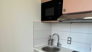 A compact kitchen with a microwave, sink, and stove. - Comfort Studio in a Premium Residence- Sport/cinema (Huningue)