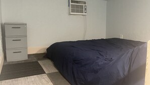 A bedroom with a bed, a desk, and an air conditioning unit. - Tiny House Retro Cabin (Umatilla)