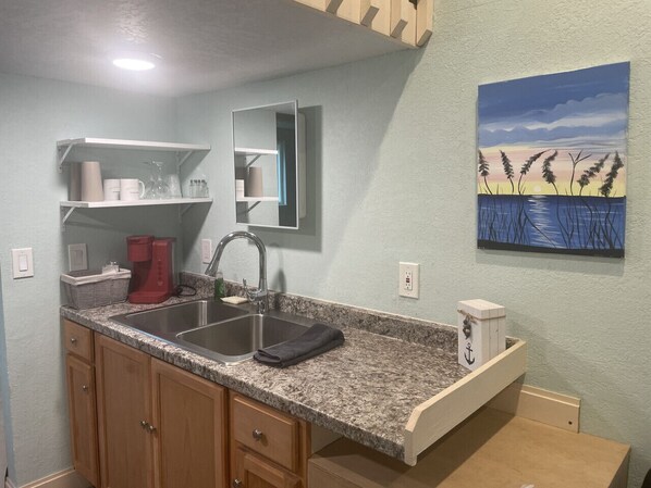 A kitchen with granite countertops, a stainless steel sink, wooden cabinets, and a built-in microwave.