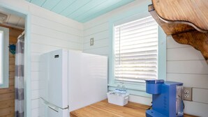 Eine Küche mit einem weißen Kühlschrank, einer Holz Arbeitsplatte, einem Fenster mit Jalousien und einer blauen Kaffeemaschine.
