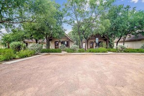 A residential area with two houses, a gravel driveway, and surrounding greenery.