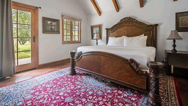 Ein Schlafzimmer mit einem großen Bett, einem Holzkopfbrett und einem roten Teppich mit Muster.