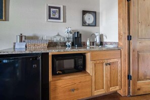 Eine kompakte Küche mit integriertem Mikrowellenherd, einer Kaffeemaschine und einem Geschirrgestell.