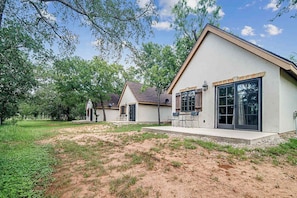A modern house with a large patio area, a covered outdoor seating area, and a well-maintained lawn.