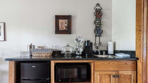 Een kleine keuken met een zwarte koelkast, een magnetron en een houten kastje.