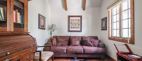 A cozy room with a patterned sofa, wooden cabinet, and a cowhide rug.