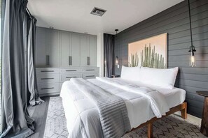 Ein Schlafzimmer mit einem Bett, einem grauen Kleiderschrank und einem Wandbild mit einem Kaktus.