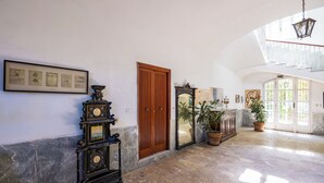 A spacious hallway with a wooden door, a wall-mounted clock, and a framed picture collection.